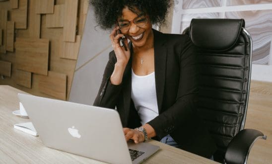 Black business professional on the phone while working at a laptop