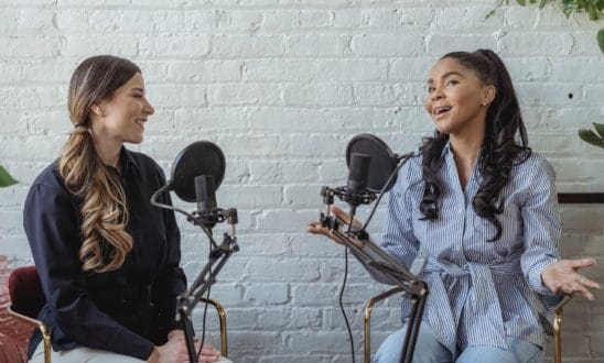 Two women talking with podcast microphones